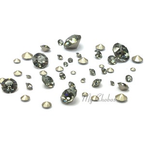 Puede incluir: Surtido de piedras de cristal negro de varios tamaños esparcidas sobre una superficie blanca.