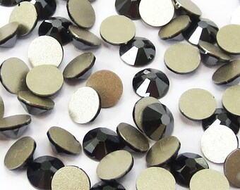 May include: A collection of black and silver rhinestones, some with a flat back and some with a pointed back.
