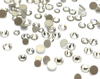 Puede incluir: Una dispersión de piedras de cristal transparentes sobre un fondo blanco. Las piedras de cristal son de varios tamaños y formas.
