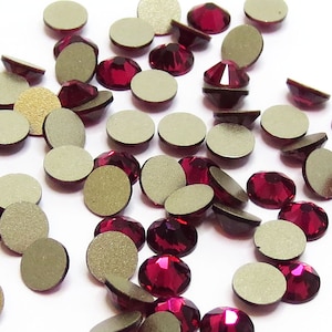May include: A scattering of red rhinestones with silver backs. The rhinestones are round and have a faceted design.