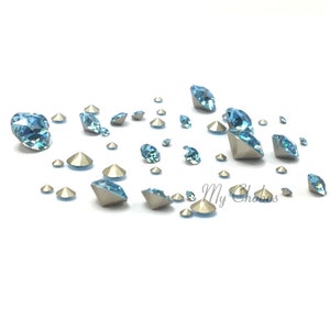 Puede incluir: Surtido de piedras de cristal azul claro de varios tamaños esparcidas sobre una superficie blanca.