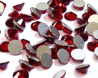 May include: A scattering of red crystal rhinestones with silver backing. The rhinestones are various sizes and shapes.