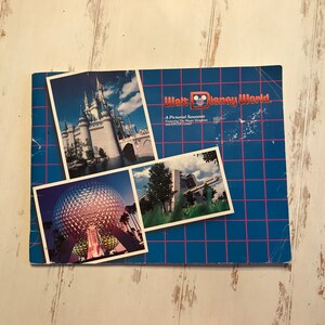 May include: A vintage Walt Disney World pictorial souvenir featuring images of Cinderella's castle, Spaceship Earth, and other attractions. The cover is blue with a grid pattern and the words "Walt Disney World."