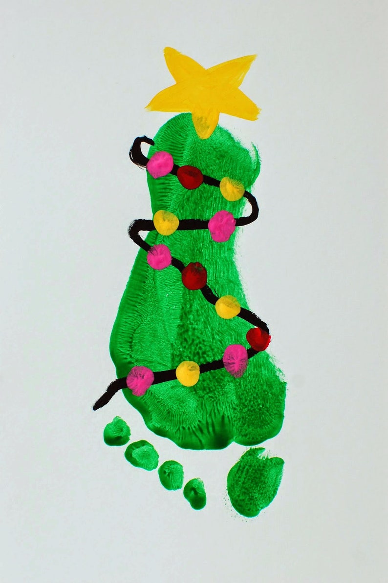 May include: A green handprint shaped like a Christmas tree with a yellow star on top. The tree is decorated with a black string of lights with pink and yellow bulbs.