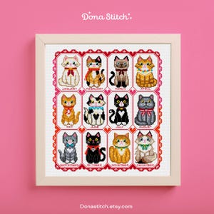 May include: A framed cross-stitch depicting twelve cats, one for each month. The cats are in different colours and patterns, each wearing a decorative collar. The artwork is in a light-coloured wooden frame, with the text "Dona Stitch" at the top.