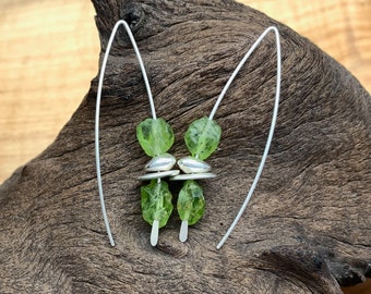 May include: A pair of silver earrings featuring green gemstone beads. The earrings are crafted from thin silver wire and have a minimalist design.