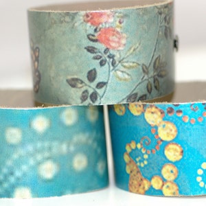 May include: Three fabric-covered cardboard rings. The top ring has a floral pattern in shades of blue, green, and pink. The middle ring has a blue background with white dots. The bottom ring has a blue background with yellow and orange circles.