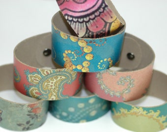 Può includere: Un set di sei braccialetti in pelle colorati con diversi motivi. I braccialetti sono impilati a forma di piramide, con il braccialetto superiore rosa e giallo, il secondo braccialetto blu e giallo, il terzo braccialetto rosa e oro, il quarto braccialetto blu e bianco, il quinto braccialetto rosa e grigio, e il sesto braccialetto verde e oro.