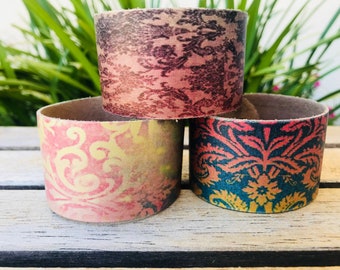 Può includere: Tre braccialetti in pelle con un motivo damascato rosa, giallo e blu.