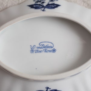 May include: A white oval serving dish with a blue floral design and the words "Vienna Woods Fine China" on the bottom.