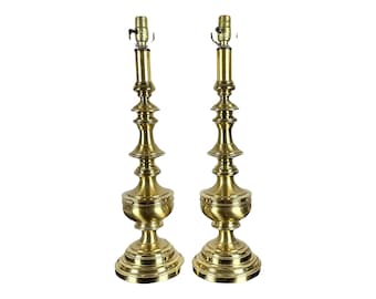May include: A pair of tall, gold-toned table lamps with a classic, ornate design. Each lamp features a tiered, fluted base and a round, bulbous shade holder.