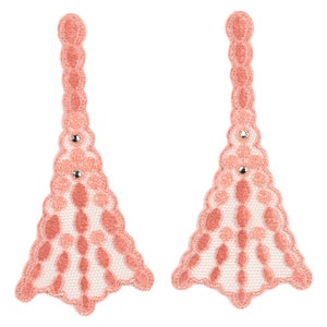 May include: Two coral-colored lace appliques, each shaped like a stylized Eiffel Tower. The appliques feature a scalloped edge and a delicate openwork design. Small silver-colored embellishments are placed on each applique.