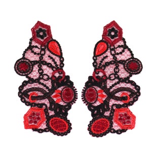 May include: Two red and black lace appliques featuring intricate floral and chain designs. The appliques are ideal for adding a touch of elegance to any project.