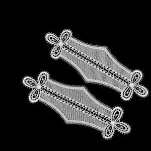 Puede incluir: Dos bordes de encaje blanco con un diseño floral. El encaje es delicado e intrincado, con un patrón repetitivo de pequeñas flores y hojas.