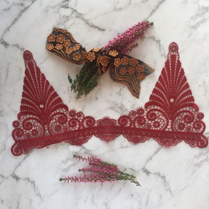 Könnte beinhalten: Rote Spitzenborte mit einem gewellten Rand und einem zarten Blumenmuster. Die Spitze ist perfekt, um jedem Projekt einen Hauch von Eleganz zu verleihen.
