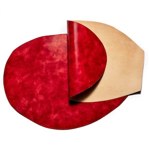 May include: A red leather sheet with a tan leather sheet folded over it. The red leather has a marbled effect.
