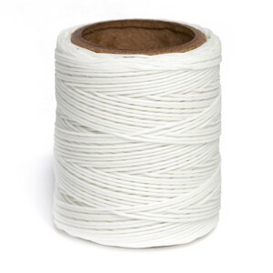 May include: A spool of white waxed thread, wound tightly on a cardboard tube.