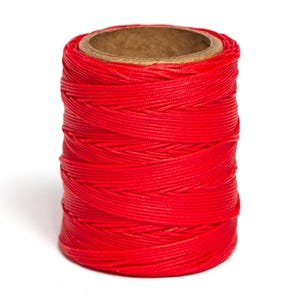 May include: A spool of bright red thread wound around a cardboard tube.