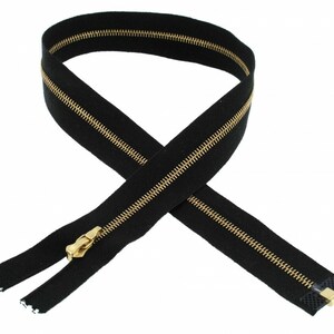 May include: A black zipper with gold teeth. The zipper is laid out in a figure eight shape.