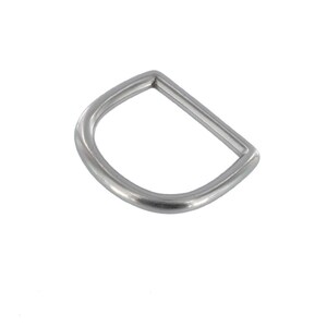 May include: A single, silver-colored D-ring, a metal hardware component, is shown against a white background. The ring has a rounded D shape with a flat, straight side and a curved side. The metal has a matte finish.