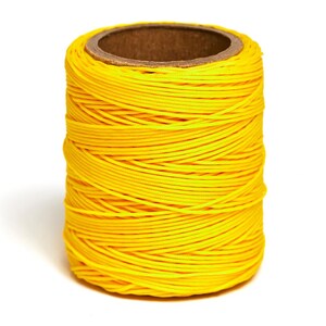 May include: A spool of bright yellow thread wound tightly on a cardboard tube.