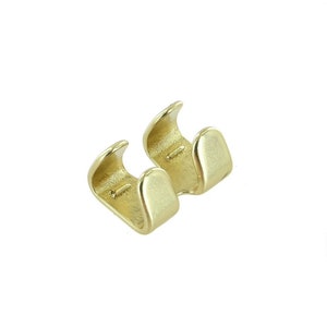 Könnte beinhalten: Zwei goldfarbene Metallverschlüsse für eine Kette oder ein Armband. Die Verschlüsse sind U-förmig mit einer kleinen Öffnung an einer Seite.
