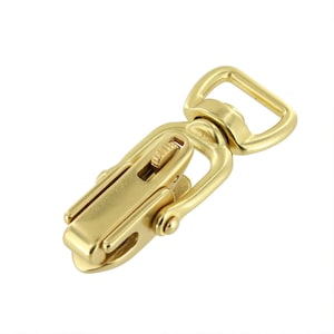 May include: Gold-toned metal swivel snap hook with a spring-loaded latch. The hook has a D-ring on one end and a swiveling mechanism on the other.