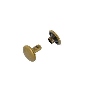 May include: A set of two antique brass rivets, one with a flat head and the other with a round head. The rivets are used for attaching fabric or leather to other materials.