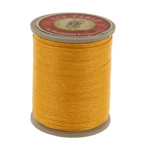 May include: A spool of yellow linen thread with a label that reads "Lin Cable 50 Grs. Ets. Toulemonde Successeurs."