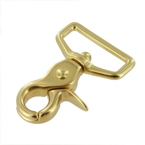 May include: Gold-toned metal swivel snap hook with a rectangular loop. The hook is designed for attaching to straps, leashes, or other items.