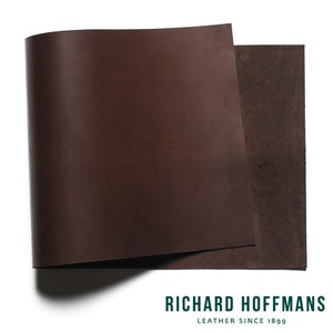 May include: A close-up of a brown leather sheet folded in half. The leather is smooth and has a slight sheen. The sheet is labeled "Richard Hoffmans Leather Since 1899".