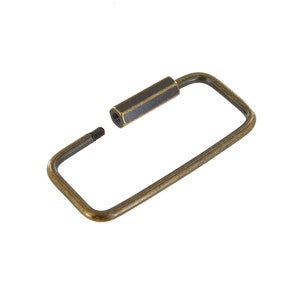 May include: A brass key ring with a rectangular shape and a screw-on closure.
