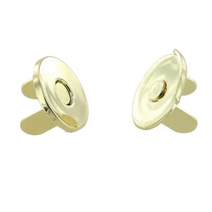 May include: Two gold-toned magnetic closures for sewing projects. Each closure has a round, flat top with a smaller round magnet in the center. The closures have two prongs on the bottom.