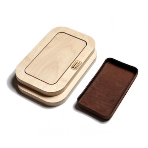 May include: A stack of two light-colored wooden rectangular trays with rounded corners and a separate dark brown rectangular tray with a smooth interior surface. The top wooden tray features a small rectangular logo with the text Blackdog.