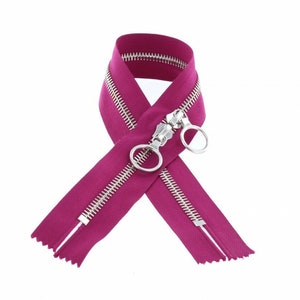 May include: A pink zipper with silver teeth and a silver slider. The zipper is folded in half and tied in a knot.