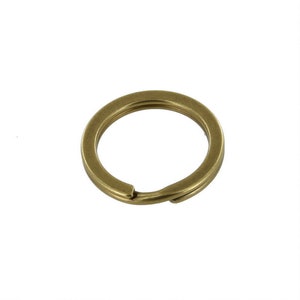 May include: A brass key ring with a simple, circular design. The ring is made of solid brass and has a smooth, polished finish.