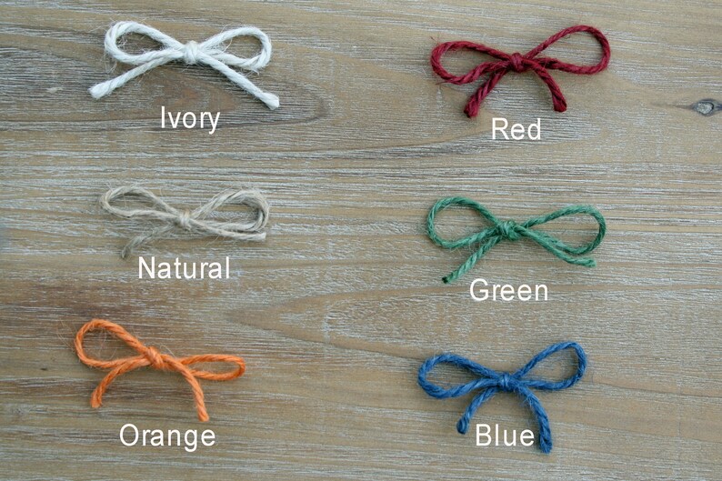 May include: Six different colors of twine tied into bows. The colors are ivory, red, natural, green, orange, and blue.