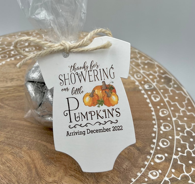 May include: A white onesie shaped thank you tag with the text "Thanks for showering our little pumpkin's arriving December 2022". The tag has a small illustration of three pumpkins.