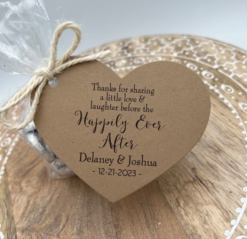 Puede incluir: Una tarjeta marr&oacute;n en forma de coraz&oacute;n con el texto "Thanks for sharing a little love & laughter before the Happily Ever After Delaney & Joshua - 12-21-2023 -" impreso en marr&oacute;n.