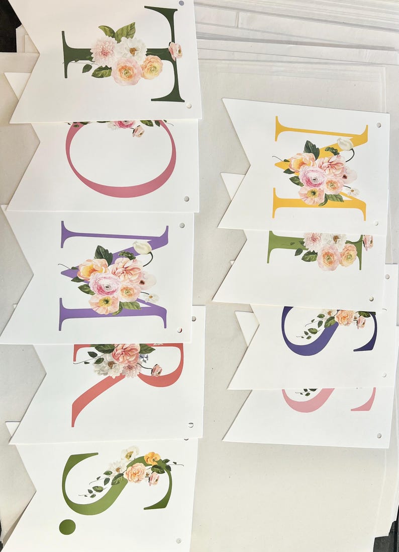 May include: A floral banner with the word "SPRING" spelled out in colorful letters. Each letter is decorated with a bouquet of pink, white, and yellow flowers.