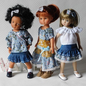 May include: Three dolls wearing different outfits. The doll on the left is wearing a blue floral top and a denim skirt. The doll in the middle is wearing a blue and yellow floral dress with a denim skirt. The doll on the right is wearing a white top with a denim skirt with a floral trim.