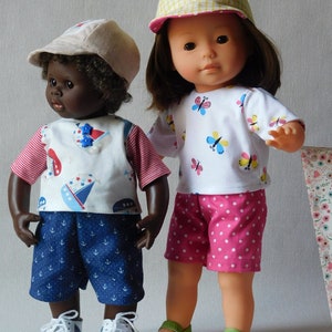 Peut inclure: Deux poupées portant des tenues d'été. Une poupée a la peau brune et porte une chemise rayée bleu et blanc, un short bleu avec des ancres blanches, une casquette de baseball beige et des baskets blanches. L'autre poupée a la peau claire et porte une chemise blanche avec des papillons multicolores, un short rose à pois blancs, une casquette de baseball vichy jaune et blanc et des chaussures vertes.