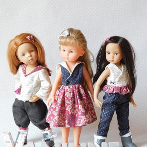 May include: Three dolls with different hair colors and outfits stand in front of a white background. The dolls wear dresses, pants, and tops in various colors and patterns. The word "VANILINE" is spelled out in front of the dolls.