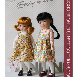 May include: Two dolls wearing floral print dresses and white tights. The dolls are standing in front of a white background with the text "Basiques d'hiver" and "SOUS-PULL, COLLANTS ET ROBE CROISÉE" in French. The dolls are wearing black and burgundy shoes.