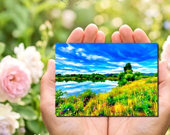 May include: A rectangular print featuring a vibrant landscape painting of a calm blue lake reflecting a bright sky with white clouds, surrounded by a lush meadow filled with yellow, green, and colorful wildflowers under a clear blue sky.
