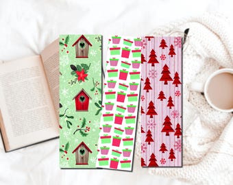 May include: Three rectangular bookmarks featuring holiday designs. The first is light green with red birdhouses, holly, and snowflakes. The second has a white background with a pattern of pink and green gift boxes. The third has red trees.