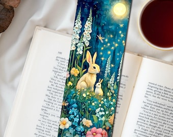 May include: A rectangular bookmark featuring a vibrant illustration of two rabbits in a lush garden at night, surrounded by tall white foxglove flowers, colorful blossoms, and a glowing full moon in a deep blue starry sky.
