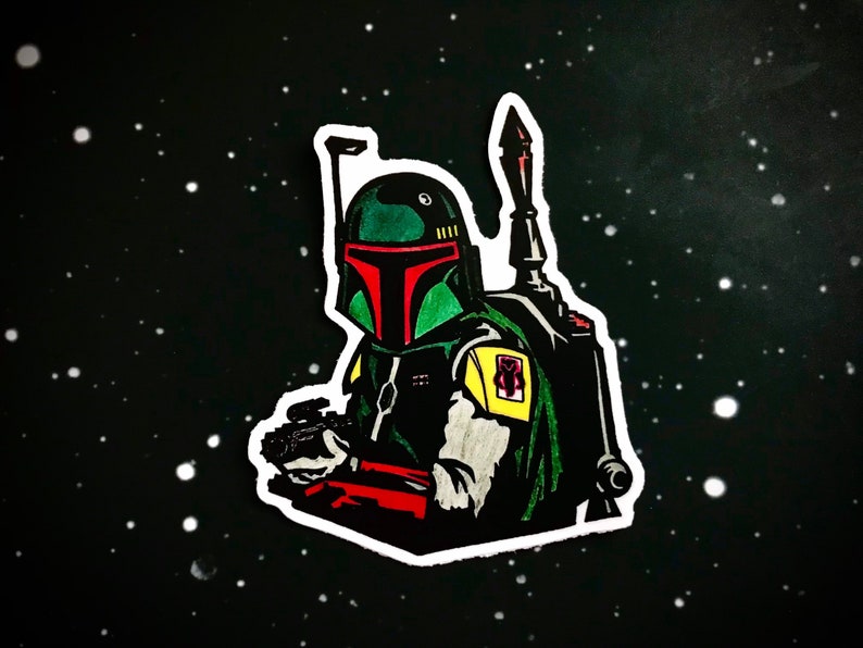 May include: A green and red Boba Fett character sticker with a white outline. The sticker is set against a black background with white dots.
