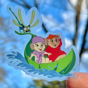 May include: A sticker featuring two cartoon mice riding a green leaf boat with a dragonfly on top. The mice are wearing hats and the boat is floating on blue water.