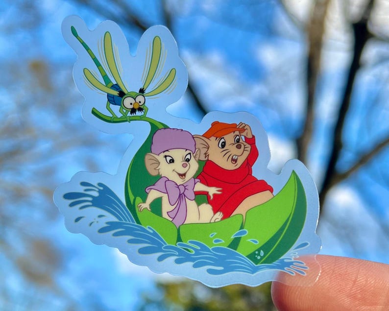 May include: A sticker featuring two cartoon mice riding a green leaf boat with a dragonfly on top. The mice are wearing hats and the boat is floating on blue water.